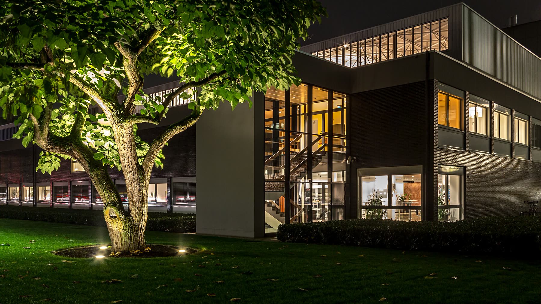 Modernes Verwaltungsgebäude in der Abenddämmerung mit warm beleuchteten Fenstern