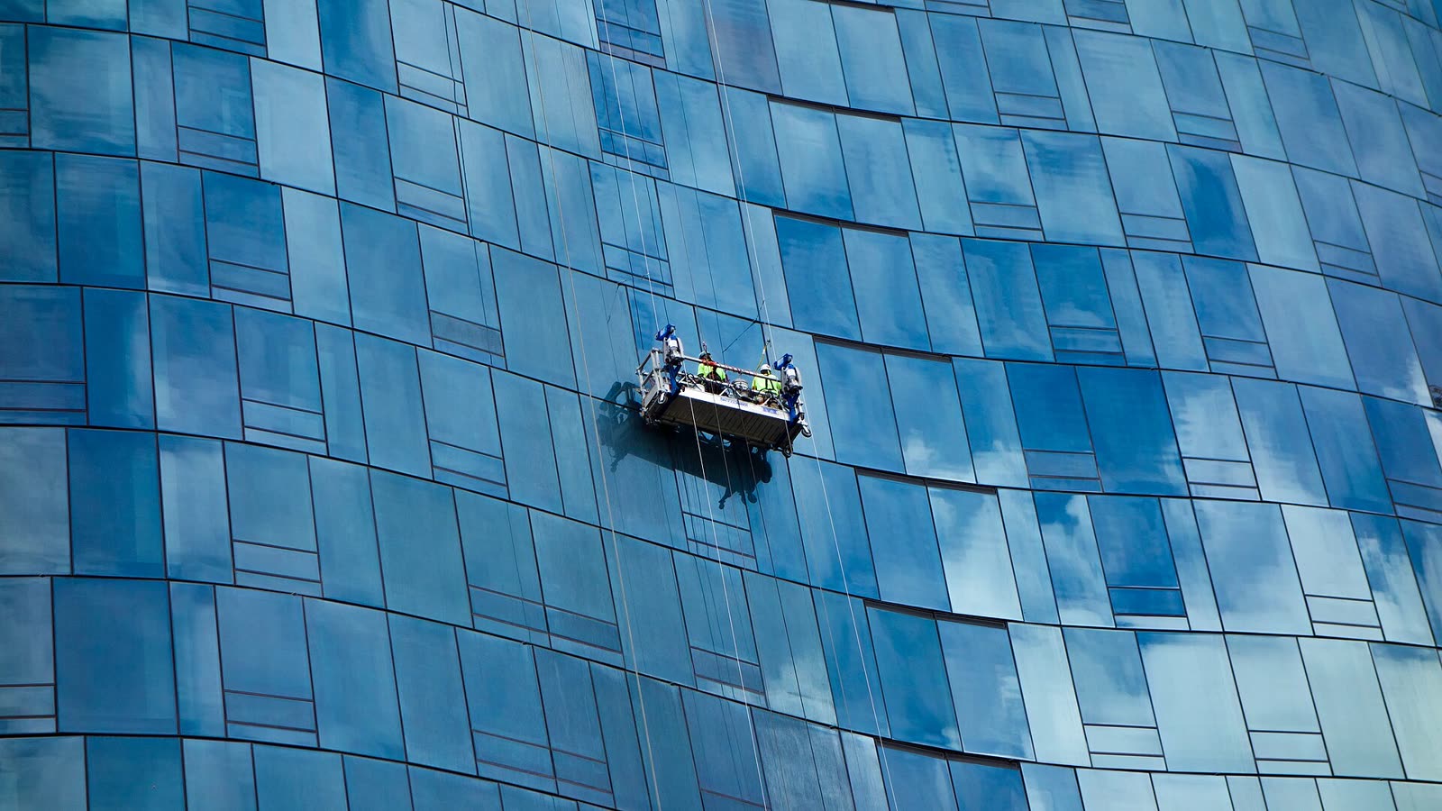 Blaue Glasfassade mit Arbeitskorb an der Außenseite